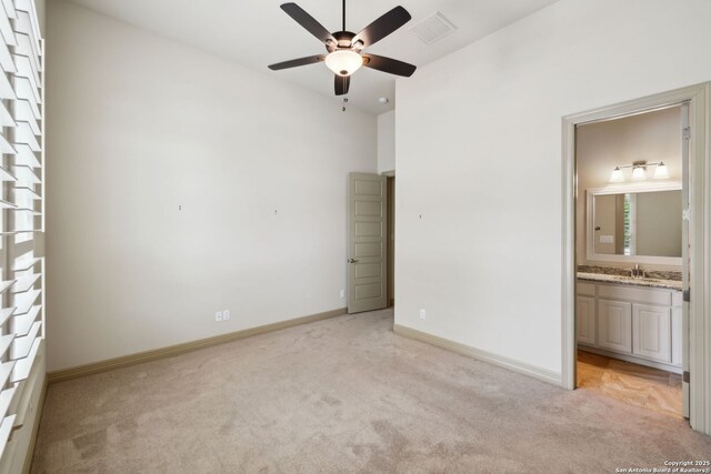 unfurnished bedroom featuring light colored carpet, a sink, baseboards, ensuite bathroom, and visible vents