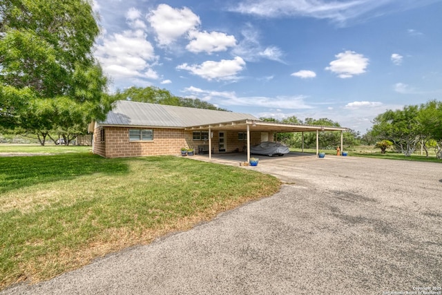 view of front of house featuring a carport, driveway, metal roof, and a front yard