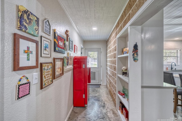 hall featuring a sink, a textured wall, and concrete flooring