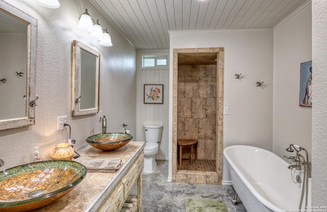 full bathroom featuring crown molding, toilet, a freestanding bath, and a sink