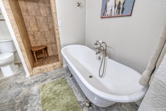 full bath featuring toilet, a freestanding tub, a textured wall, and tiled shower