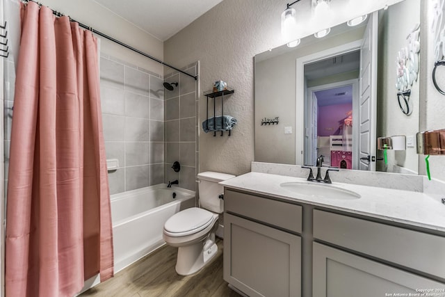 bathroom featuring wood finished floors, shower / tub combo, vanity, toilet, and a textured wall