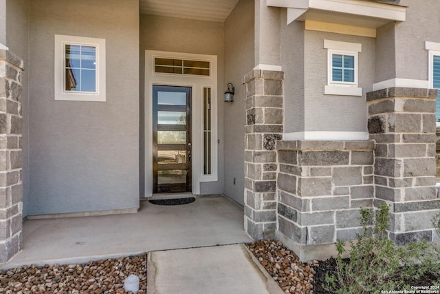 view of exterior entry featuring stucco siding and stone siding