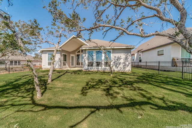 back of house with fence, stucco siding, and a yard