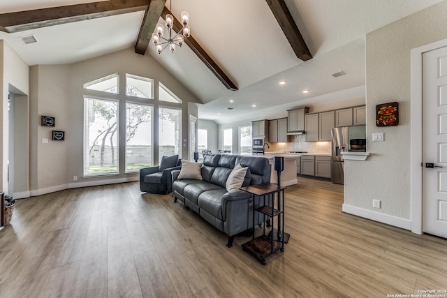 living room featuring a notable chandelier, light wood-style flooring, baseboards, beamed ceiling, and visible vents