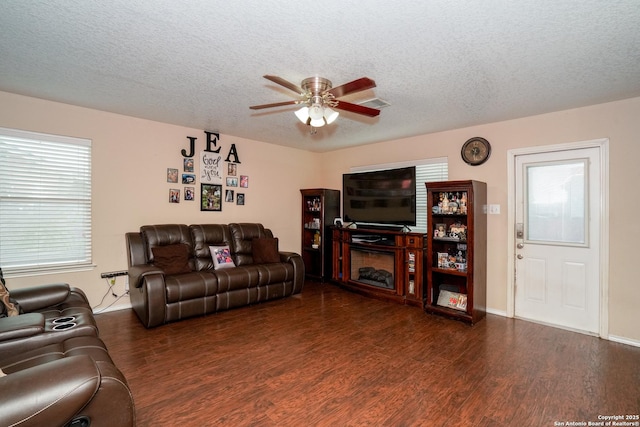 living room featuring a textured ceiling, a ceiling fan, wood finished floors, and visible vents
