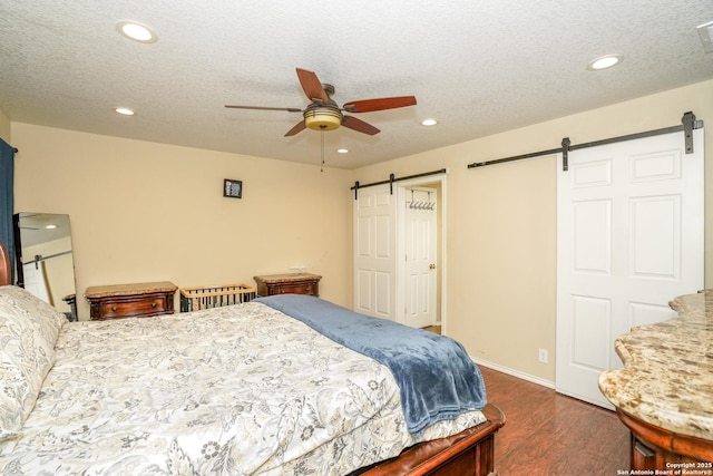 bedroom with recessed lighting, a barn door, and dark wood-type flooring