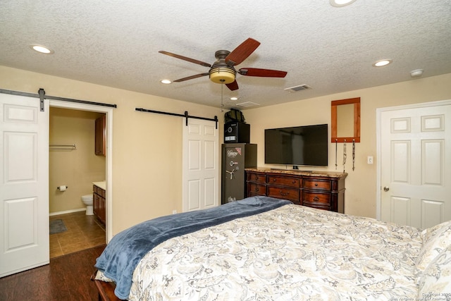 bedroom featuring ceiling fan, a barn door, a textured ceiling, recessed lighting, and visible vents