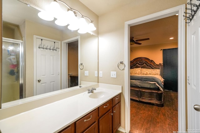 ensuite bathroom with a ceiling fan, a stall shower, wood finished floors, vanity, and ensuite bath