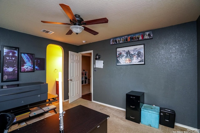 interior space featuring arched walkways, a ceiling fan, carpet flooring, and a textured ceiling