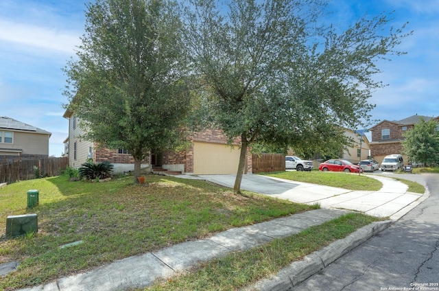 view of property hidden behind natural elements featuring fence, a front lawn, brick siding, a garage, and concrete driveway