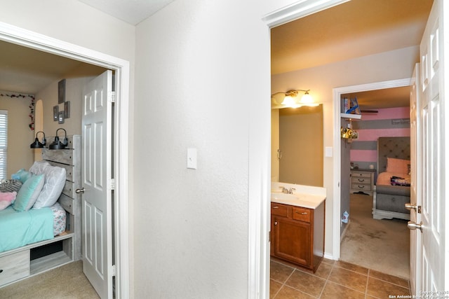 corridor with light tile patterned flooring, baseboards, light colored carpet, and a sink