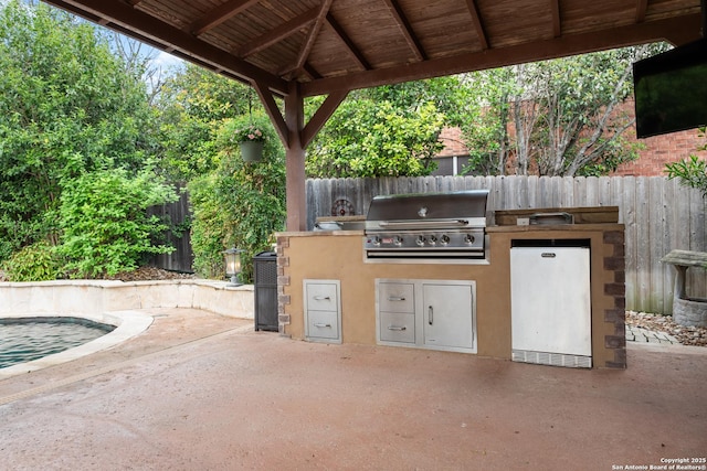 view of patio / terrace featuring a gazebo, a fenced backyard, an outdoor kitchen, and a grill