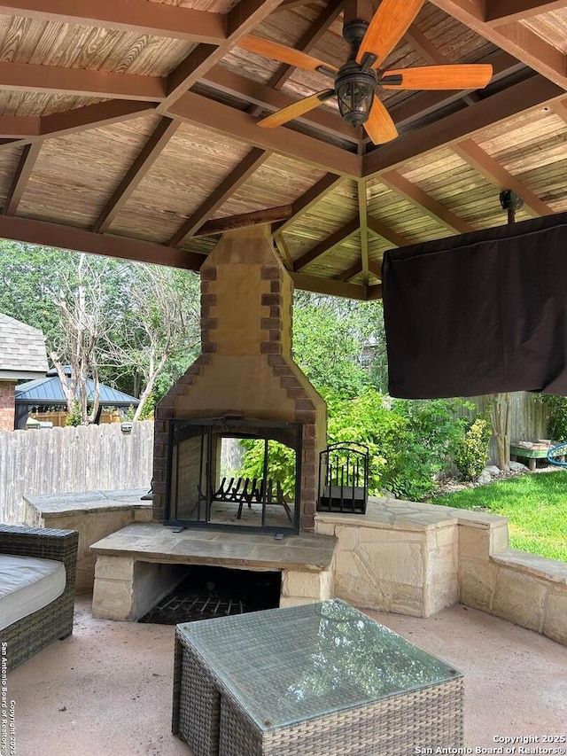 view of patio / terrace featuring a multi sided fireplace, ceiling fan, and fence