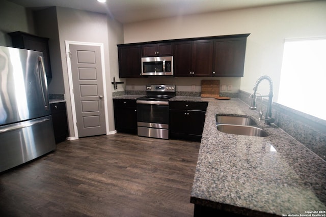 kitchen with dark brown cabinets, a sink, a peninsula, stainless steel appliances, and dark wood-type flooring
