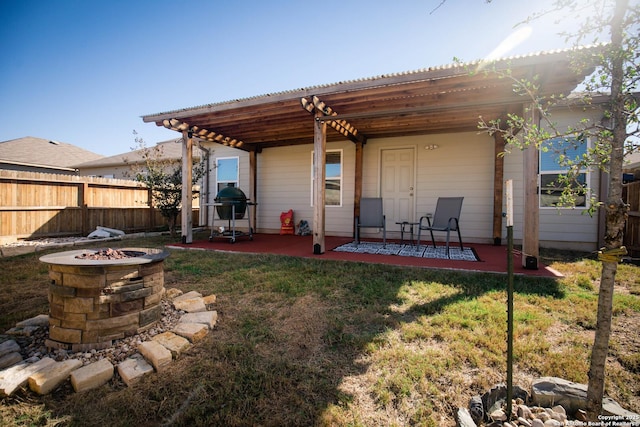 back of house with a yard, a patio, fence, and a fire pit