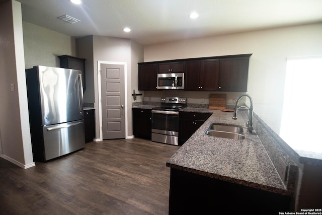 kitchen featuring visible vents, appliances with stainless steel finishes, dark wood finished floors, a sink, and a peninsula