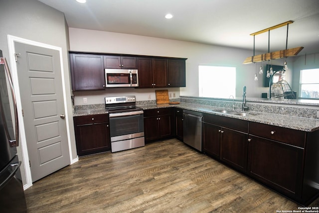 kitchen featuring dark wood-style flooring, light stone countertops, dark brown cabinets, a sink, and stainless steel appliances