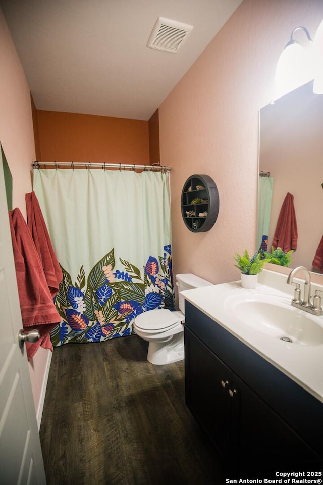 full bath with a shower with curtain, visible vents, wood finished floors, vanity, and toilet
