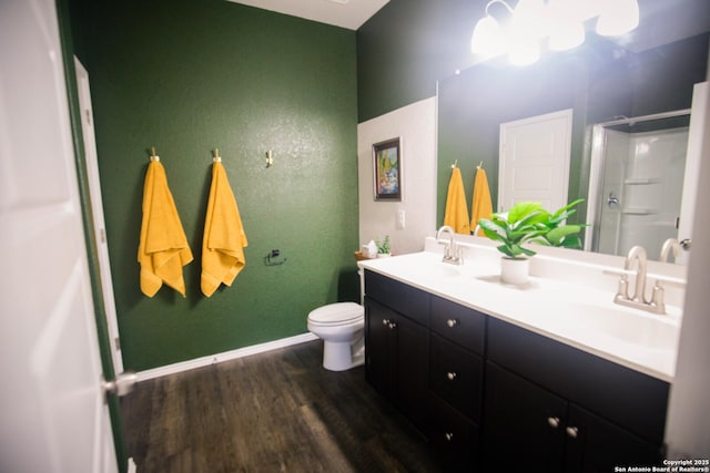 bathroom with wood finished floors, toilet, a sink, and a stall shower