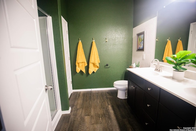 full bath featuring double vanity, wood finished floors, baseboards, a sink, and a stall shower
