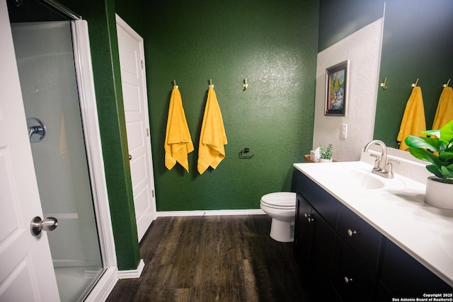 bathroom featuring vanity, a textured wall, wood finished floors, baseboards, and a stall shower