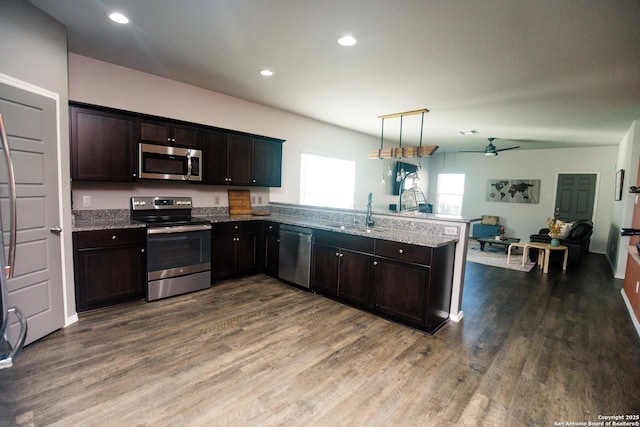 kitchen featuring a peninsula, open floor plan, dark wood-style floors, a ceiling fan, and stainless steel appliances