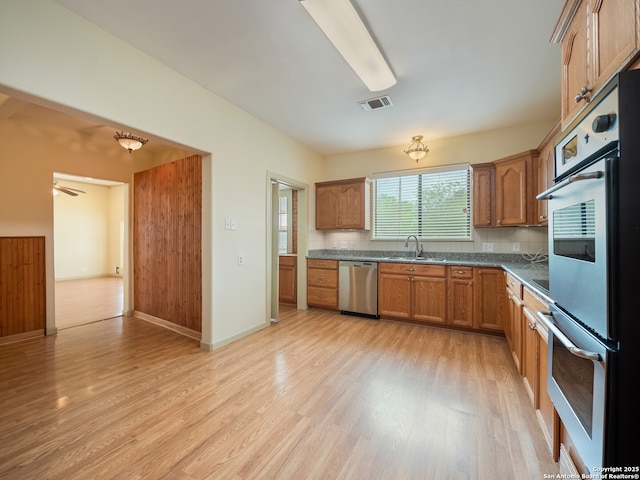 452 River Springs Dr, Seguin, TX 78155 - kitchen featuring visible vents, dark countertops, a sink, light wood finished floors, and appliances with stainless steel finishes