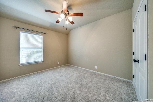 carpeted empty room featuring a ceiling fan, baseboards, and vaulted ceiling