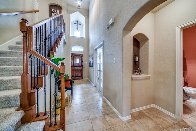 entrance foyer featuring stairway, tile patterned floors, baseboards, and arched walkways