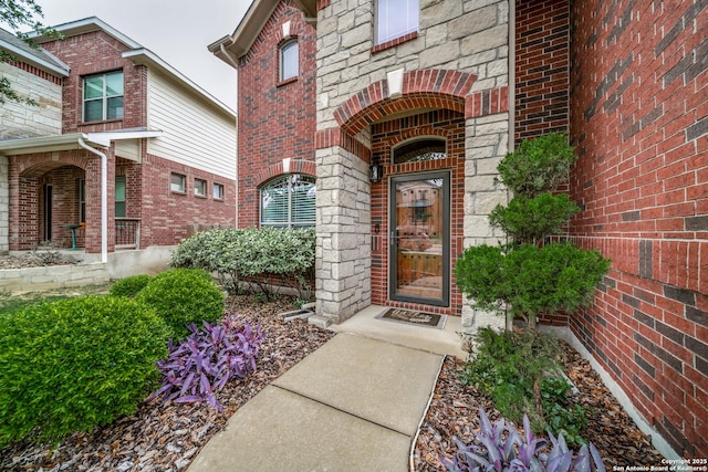 entrance to property with a porch and brick siding