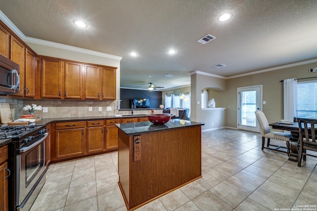 kitchen featuring crown molding, a textured ceiling, appliances with stainless steel finishes, and brown cabinets