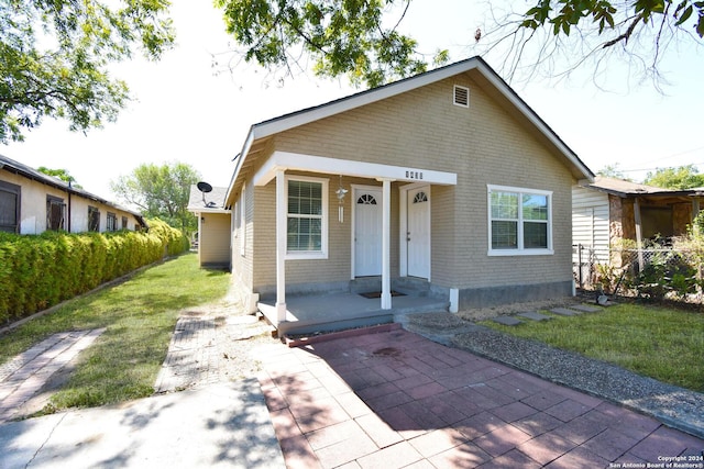 1430 Delgado St, San Antonio, TX 78207 - bungalow featuring covered porch, brick siding, and a front lawn