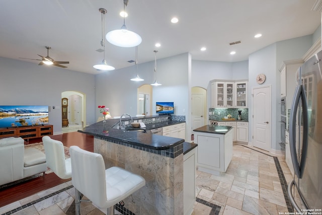 kitchen with dark countertops, visible vents, arched walkways, stainless steel appliances, and a spacious island
