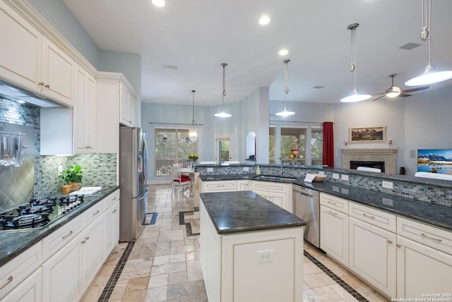 kitchen featuring stainless steel appliances, ceiling fan, decorative backsplash, and a sink