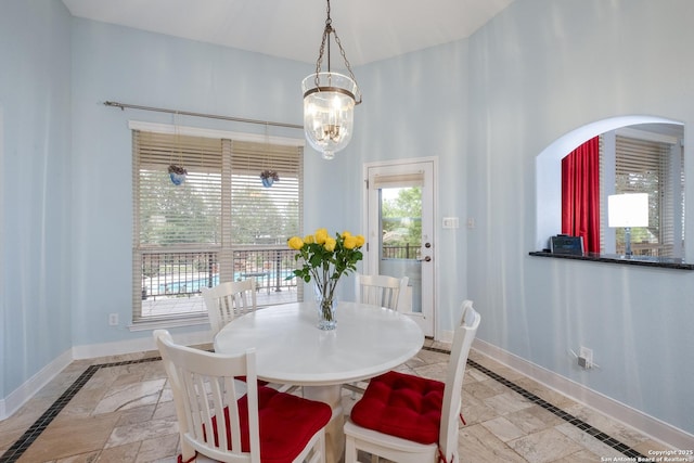 dining area with baseboards, arched walkways, and an inviting chandelier