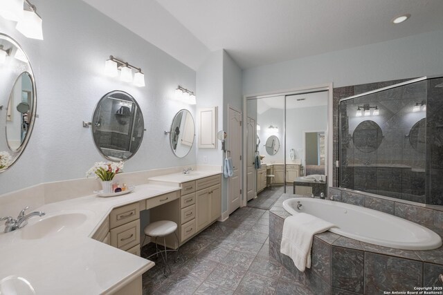full bath with double vanity, a shower stall, a sink, and a garden tub