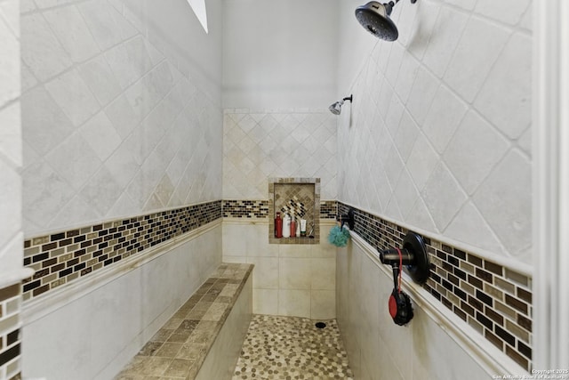 bathroom with a tile shower and tile walls