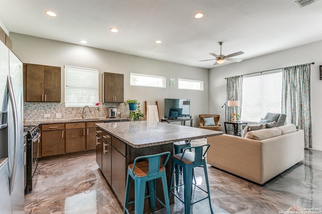 kitchen featuring recessed lighting, marble finish floor, a kitchen island, and stainless steel appliances