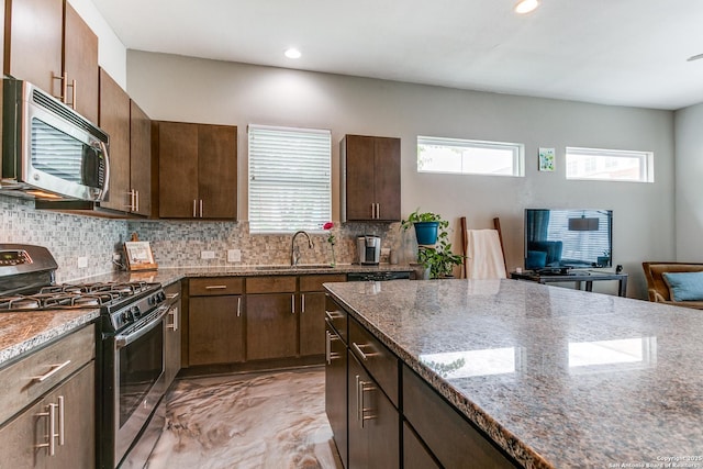 kitchen with appliances with stainless steel finishes, plenty of natural light, a sink, and tasteful backsplash