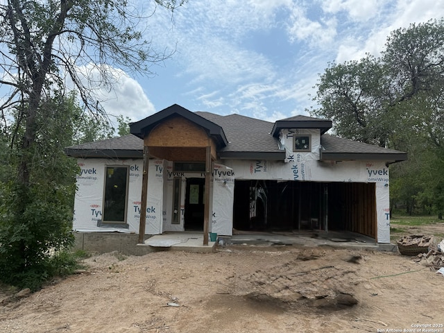 view of front of property featuring an attached garage, a shingled roof, and dirt driveway