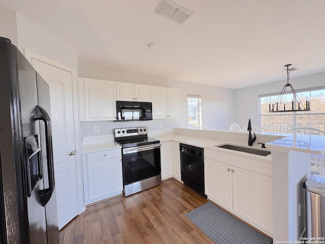 726 Barbara Dr, Canyon Lake, TX 78133 - kitchen with visible vents, a peninsula, dark wood-style floors, a sink, and black appliances