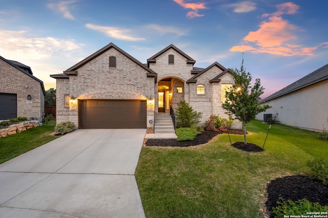 french country style house featuring cooling unit, a front lawn, concrete driveway, an attached garage, and stone siding