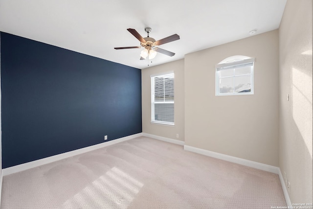 empty room featuring light colored carpet, baseboards, and ceiling fan