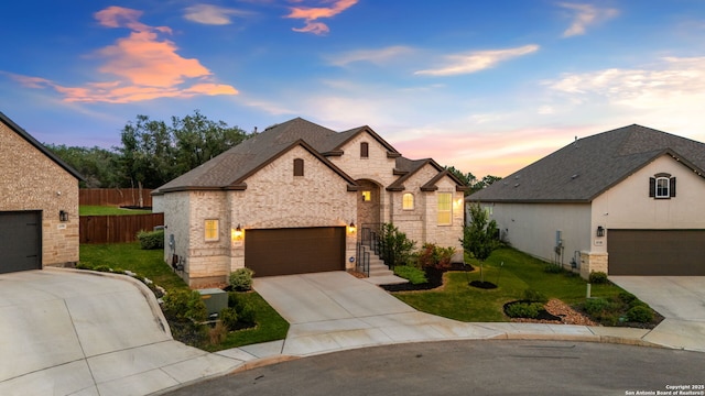french country home featuring fence, stone siding, driveway, roof with shingles, and a yard