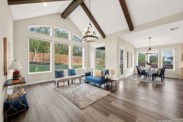 living area with visible vents, wood finished floors, beamed ceiling, baseboards, and a chandelier
