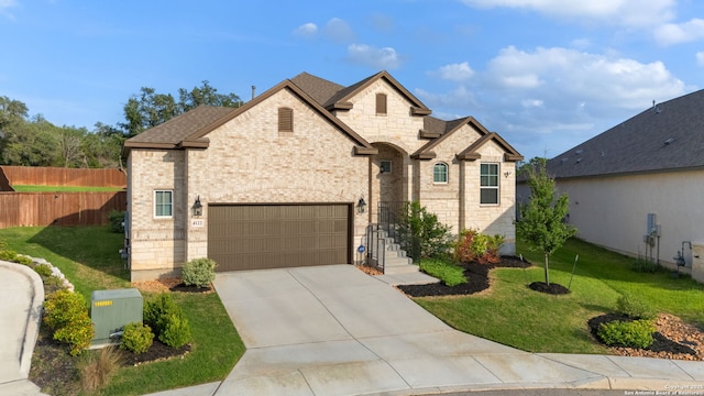 french country inspired facade featuring fence, concrete driveway, brick siding, and a front yard