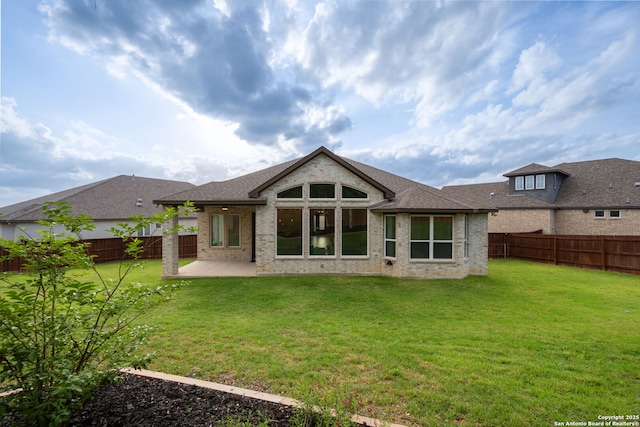 back of property featuring a lawn, brick siding, a fenced backyard, and a patio area