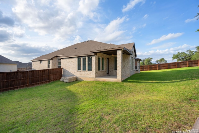 back of house with a lawn, a patio area, brick siding, a fenced backyard, and a shingled roof