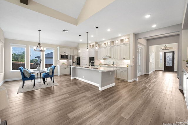 kitchen featuring appliances with stainless steel finishes, light countertops, a kitchen island with sink, a chandelier, and visible vents